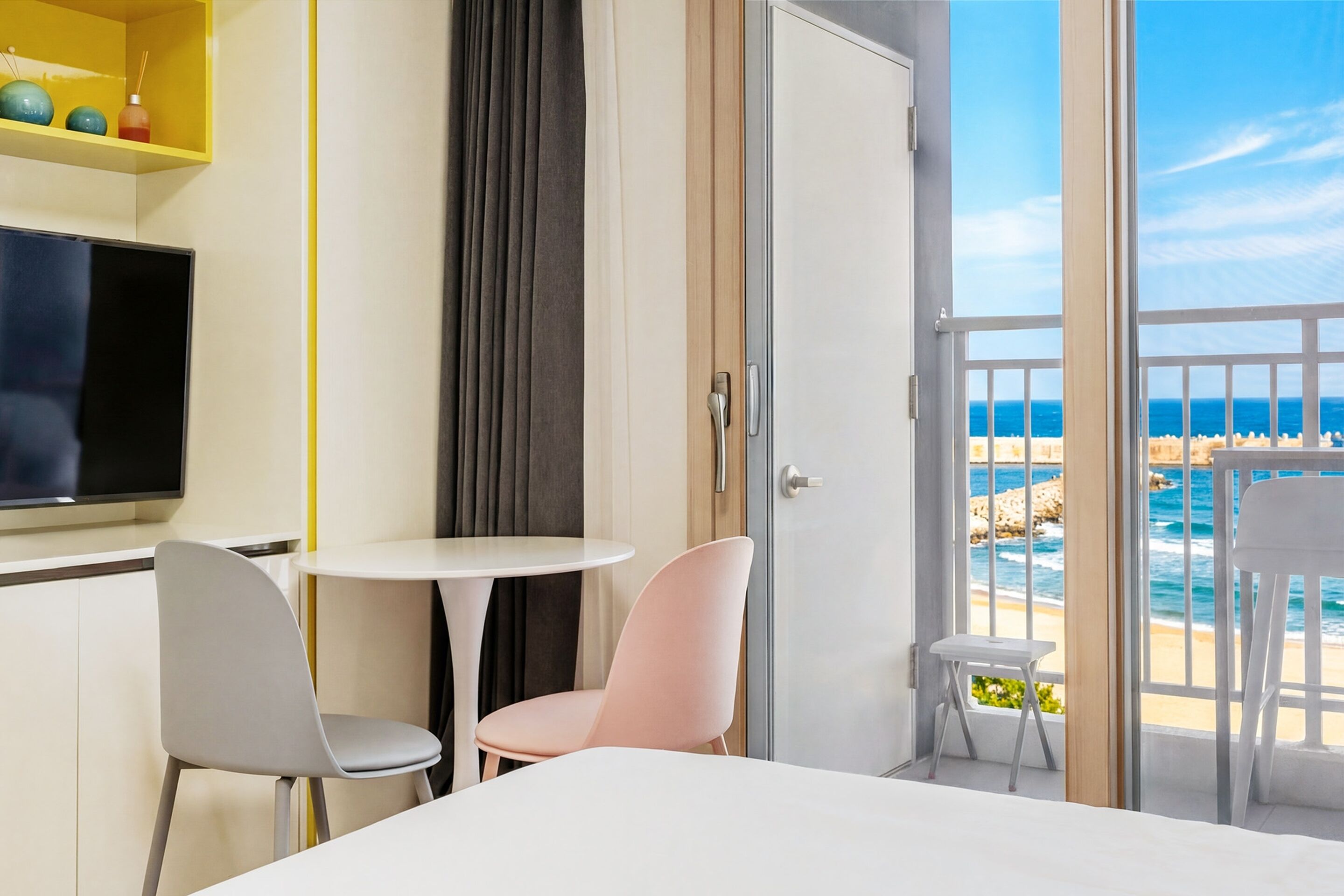 Habitación de hotel con balcón, televisión, una mesita, dos sillas y una cama.