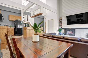 Eine moderne Küche mit Holzschränken, einem schwarzen Kühlschrank und einem Esstisch mit Stühlen.