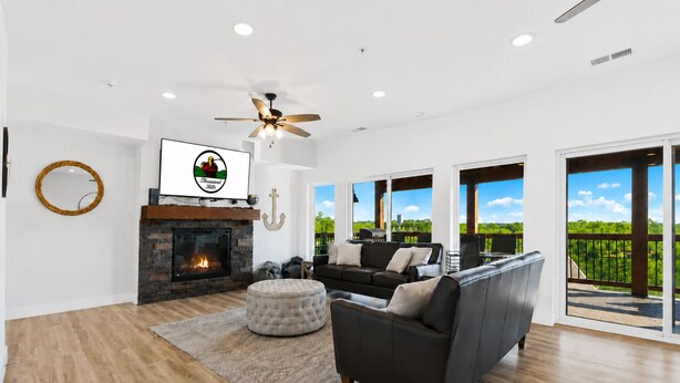 A spacious living room with a fireplace, a ceiling fan, and a large TV. - 9BR Table Rock Lake Lodge w/ Hot Tub & Game Room • Near SDC (Branson)