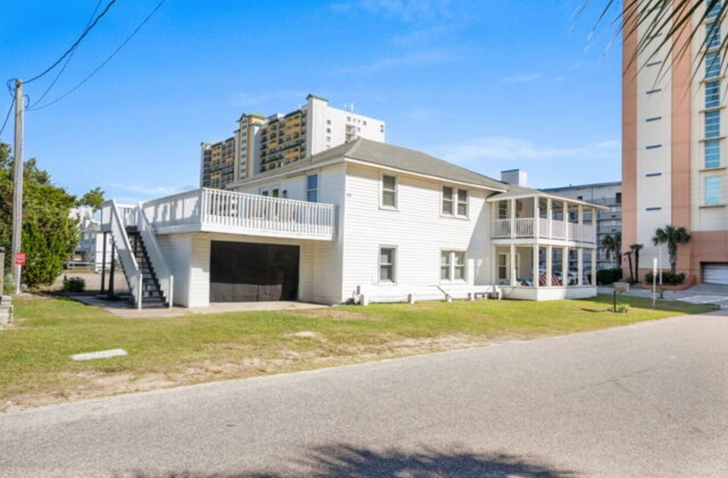 A two-story white building with a garage, a balcony, and a staircase leading to the upper level.