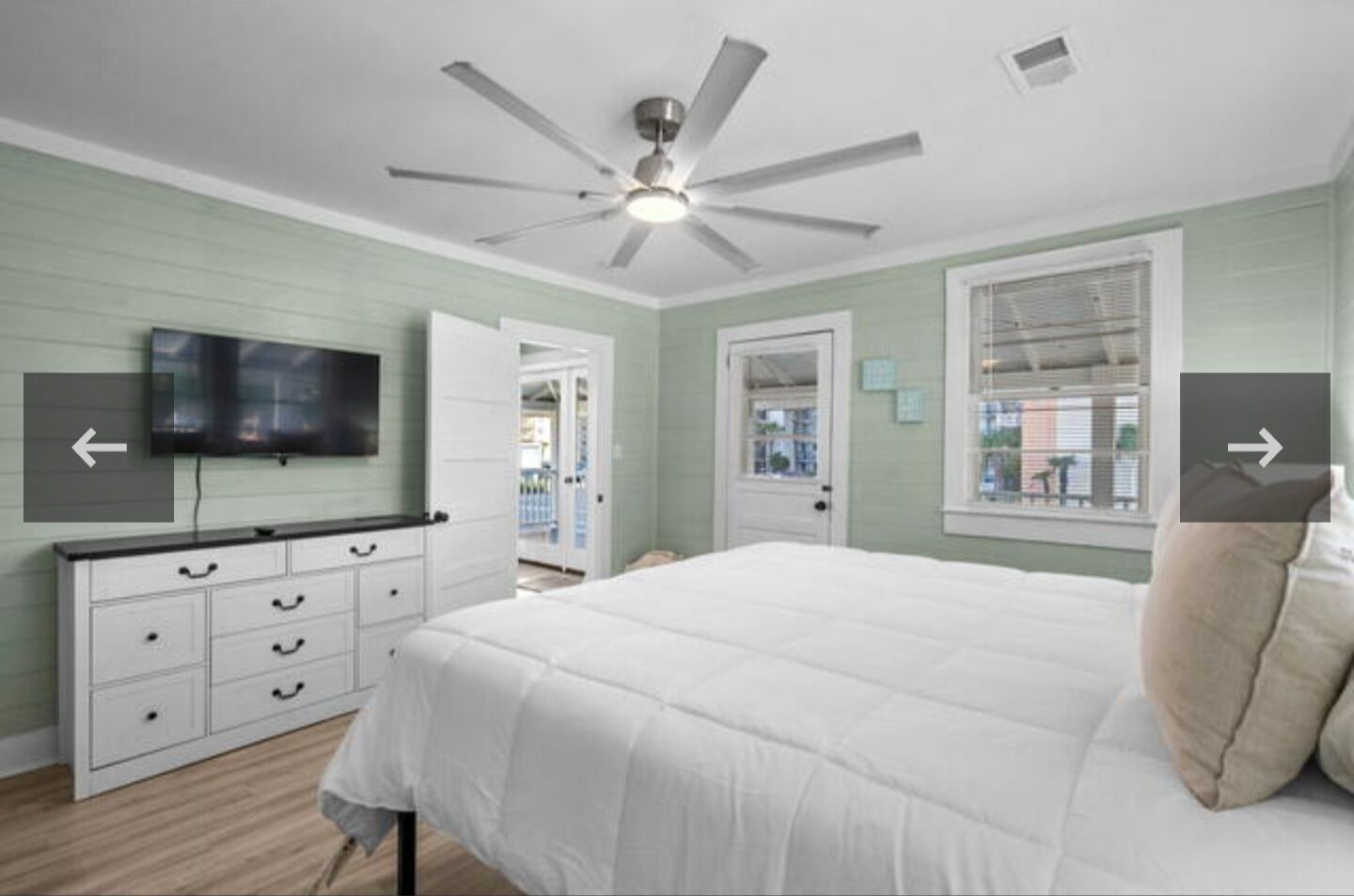 Une chambre à coucher avec un lit, un ventilateur de plafond, une télévision et une commode.