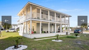Een tweelaags huis met een balkon, een voortuin en een klein gazon met planten.