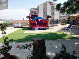 Un'area giochi all'aperto con un grande gonfiabile, uno scivolo e altalene.