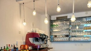 A kitchen with a bar area, a coffee machine, and a child’s high chair. - Biser Hotel (Pag)