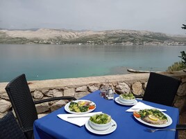Una tavola imbandita con piatti di cibo, vista su un lago e montagne sullo sfondo.