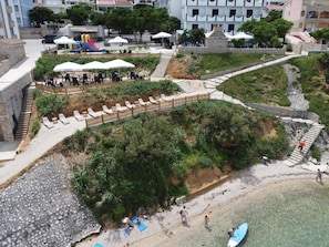 A coastal area with a sandy beach, a small water body, and a playground with slides. - Biser Hotel (Pag)