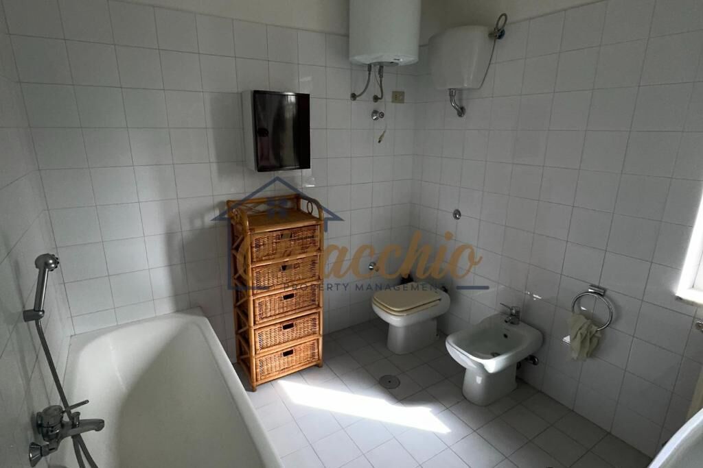 Un baño con bañera, inodoro, bidé y una cesta de mimbre.