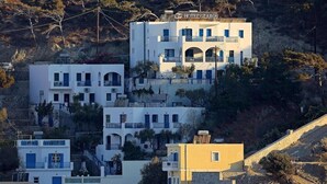 A multi-story hotel with balconies and a hillside backdrop. - Glaros Studios (Karpathos)