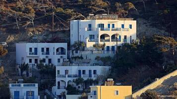 A multi-story hotel with balconies and a hillside backdrop.