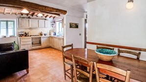 Una cocina acogedora con armarios de madera, una mesa de comedor con sillas y una lámpara colgante.