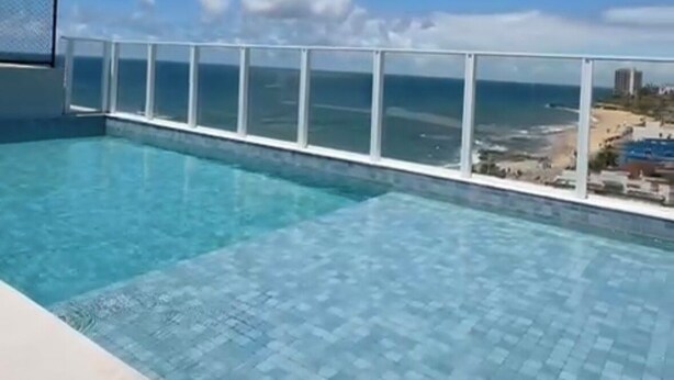 Una piscina con vista despejada al océano y una playa distante.