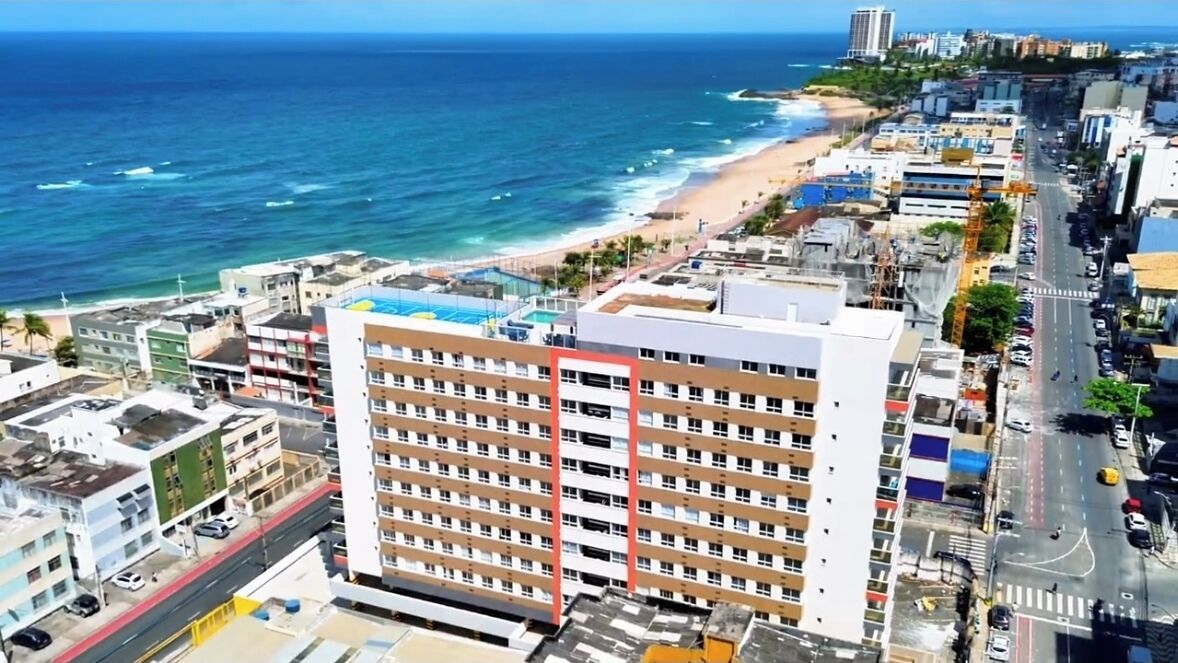 Un paisaje urbano costero con un hotel de varios pisos destacado, una playa y una vista despejada del océano.