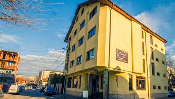 Un edificio amarillo de varios pisos con un cartel que indica que es un hotel y restaurante.