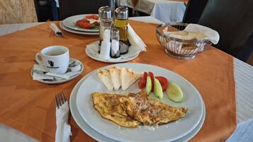 A dining table with a plate of food, a cup of coffee, condiments, and a fork.