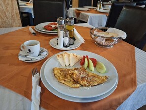Una mesa de comedor con un plato de comida, una taza de café, condimentos y un tenedor.