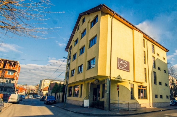 Un edificio amarillo de varios pisos con un cartel que indica que es un hotel y restaurante.