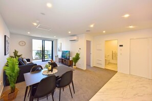 A modern living room with a dining area, a television, and a large window.