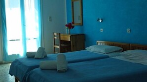 Una habitació d'hotel amb dos llits, un taulell de fusta, un ram de flors en un vas i un quadre amb marc a la paret.