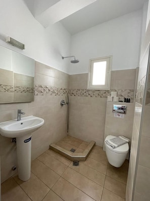 A small, modern bathroom with a sink, shower, and toilet. - Dilino AND Annex Building (Santorini)