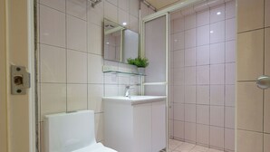 Un baño moderno con inodoro, lavamanos y zona de ducha.