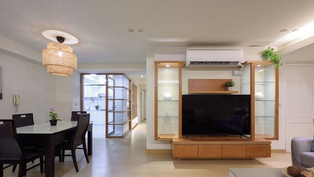 Una sala de estar moderna con un televisor de pantalla plana, muebles de madera y un comedor con mesa y sillas.