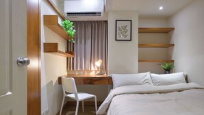 Un dormitorio con una cama, un escritorio, una silla y una planta en maceta.