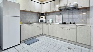 Una cocina moderna con armarios grises, un microondas integrado, una estufa a gas y un refrigerador de acero inoxidable.