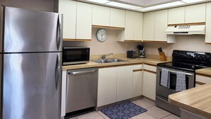A compact kitchen with stainless steel appliances, a microwave, a sink, and a stove. - 2BR Condo at Fantasy Island – Pool, Beach , Bikes (Englewood)