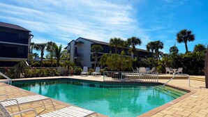 A pool area with lounge chairs and a building in the background. - 2BR Condo at Fantasy Island – Pool, Beach , Bikes (Englewood)