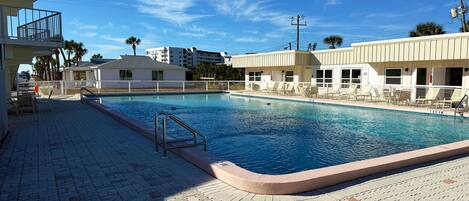 A swimming pool with lounge chairs and a lifeguard stand.