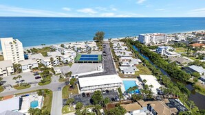 Vista aérea de un complejo turístico con piscina, canchas de tenis y un puerto deportivo.