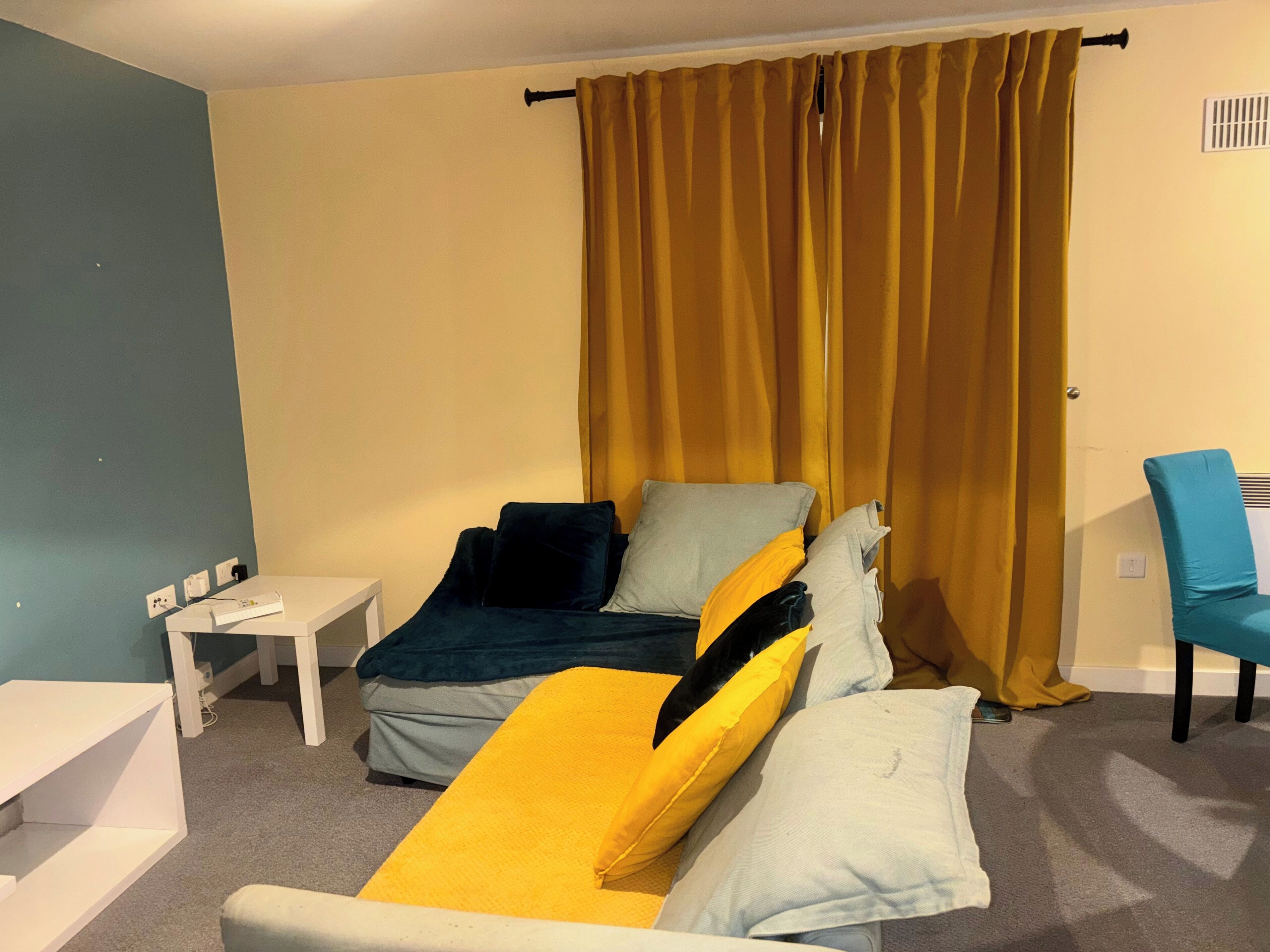 A room with a bed, a small table, a chair, and a curtain.