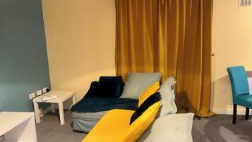 A room with a bed, a small table, a chair, and a curtain.