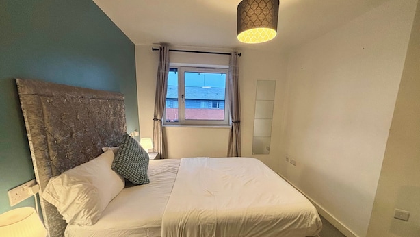 A bedroom with a bed, a headboard, a window with curtains, and a hanging light fixture. - Peaceful Urban Retreat in Wolverhampton City (Wolverhampton)