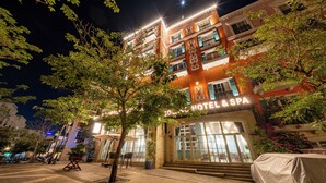 Un hôtel avec une enseigne indiquant « HÔTEL ET SPA », des places assises en plein air et un abri pour voitures.