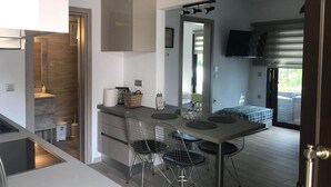 A modern kitchen with a dining area, a large mirror, and a TV mounted on the wall. - Chrysanthi Studios Apartments Pefkos (Rhodes)