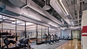 A gym with exercise equipment, large windows, and a polished floor. - Blueground | Chelsea, rooftop, nr The Vessel (New York)