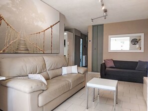Ein Wohnzimmer mit einem beigen Sofa, einem dunklen Sofa, einem weißen Couchtisch und einem wandmontierten Spiegel.