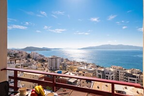 Ein Balkon mit Blick auf eine Küstenstadt und das Meer.
