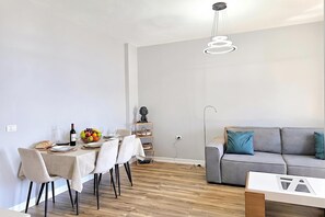 Ein zeitgemäßer Wohnraum mit Essbereich, einem grauen Sofa und einer Pendelleuchte.