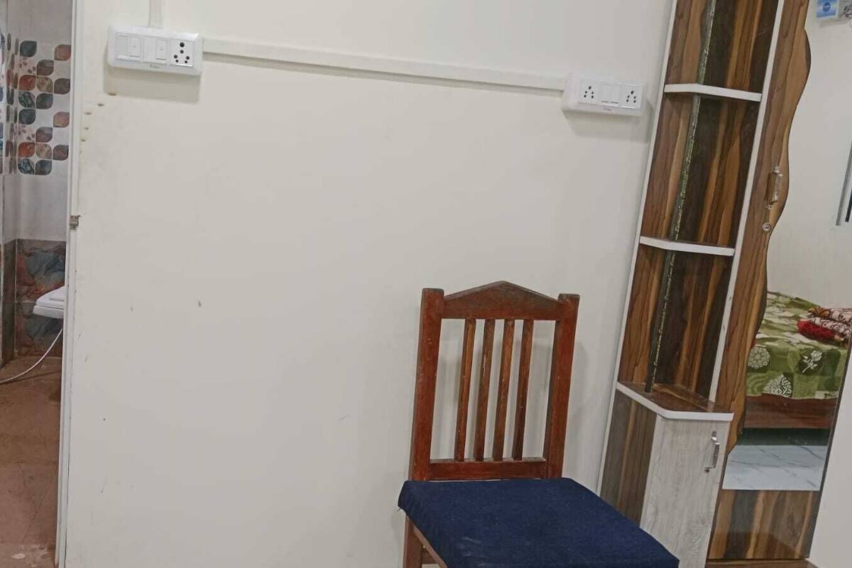 A small room with a wooden chair, a tiled wall, and a power outlet.