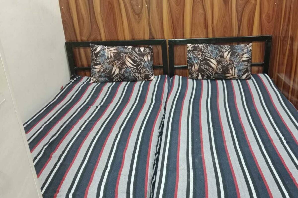 A bed with striped bedding and two patterned pillows against a wooden headboard.