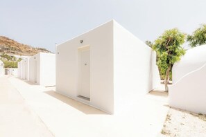 A row of white, rectangular hotel rooms with a door and a small window, aligned along a pathway. - Paradise Beach Resort - Adults Only (Mykonos)