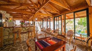 A rustic wooden interior with stone walls, a bar area, and a dining space with wicker furniture.