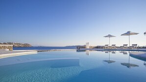 A clear blue infinity pool with a stone wall and a view of the sea. - Delight Boutique Hotel & Spa (Mykonos)