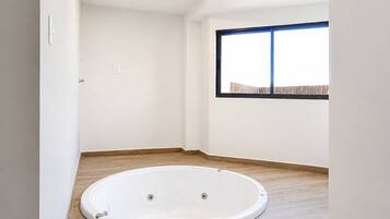 A room with a bathtub, wooden flooring, a window with a view, and a sign on the wall.