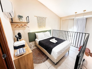 A bedroom with a bed, bedside table, wall-mounted air conditioner, and a window with curtains. - Hosts BR - MAX Carneiros Suítes (Tamandaré)