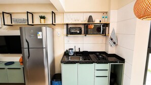 Cocina compacta equipada con refrigerador, microondas, pileta y alacenas.