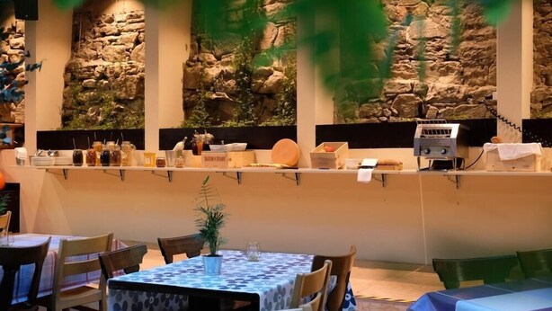 A restaurant with stone wall decor, tables with blue and white patterned tablecloths, and a variety of food items displayed on shelves. - Barabas Hotel Luzern (Lucerne)