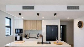 Een moderne keuken met een centraal eiland, houten krukken en inbouwapparatuur.